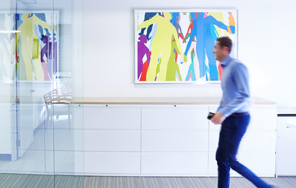 Watt Companies employee walking in front of colorful artwork